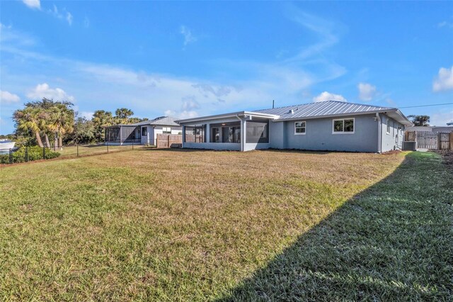 back of property featuring fence, a lawn, central AC, and a sunroom