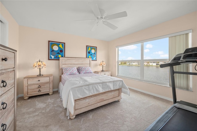 carpeted bedroom featuring a water view and ceiling fan