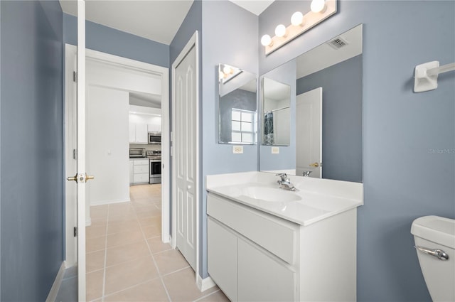 bathroom with toilet, vanity, and tile patterned floors