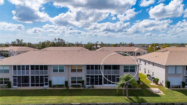 back of property with a lawn and a sunroom