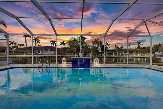 pool at dusk with a lanai, pool water feature, and a water view