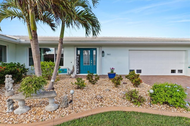 view of exterior entry featuring a garage, driveway, and stucco siding