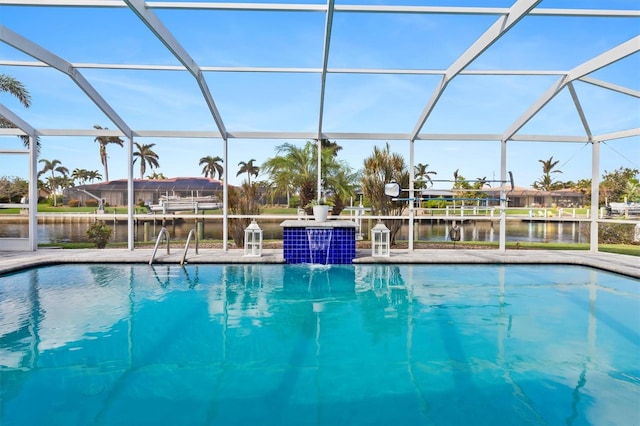 outdoor pool with a water view, glass enclosure, and a patio area