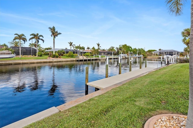 dock area featuring a water view, boat lift, and a yard