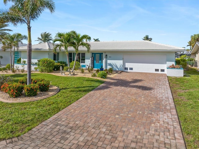 ranch-style house featuring a front yard, decorative driveway, an attached garage, and stucco siding