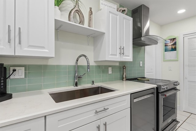 kitchen featuring appliances with stainless steel finishes, island exhaust hood, light countertops, white cabinetry, and a sink