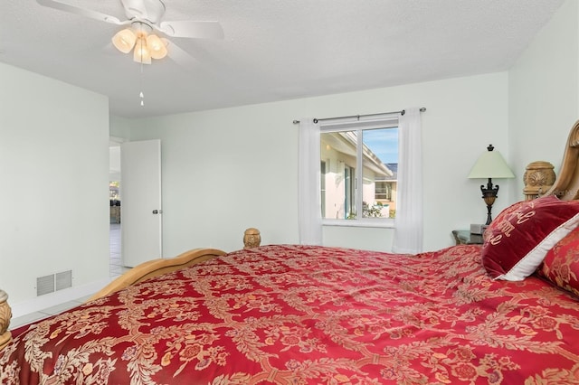 bedroom featuring a ceiling fan, visible vents, a textured ceiling, and tile patterned floors