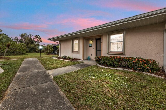 exterior entry at dusk featuring a yard