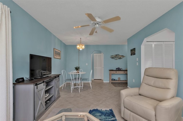 tiled living room featuring ceiling fan with notable chandelier