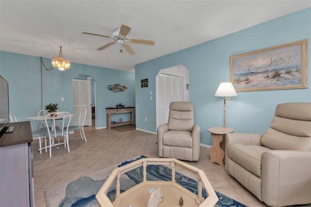 living room with ceiling fan with notable chandelier, a textured ceiling, and light tile patterned floors