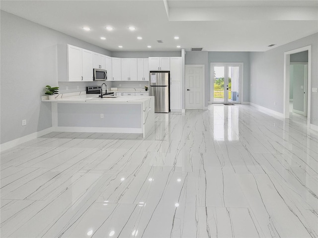 kitchen with sink, french doors, kitchen peninsula, white cabinetry, and stainless steel appliances