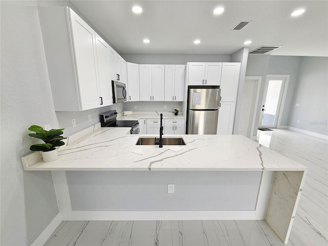 kitchen featuring kitchen peninsula, white cabinets, appliances with stainless steel finishes, light stone countertops, and sink