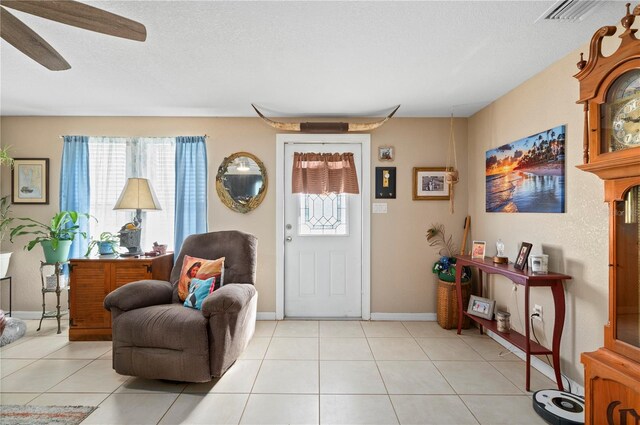 entrance foyer featuring ceiling fan, a healthy amount of sunlight, a textured ceiling, and light tile patterned flooring