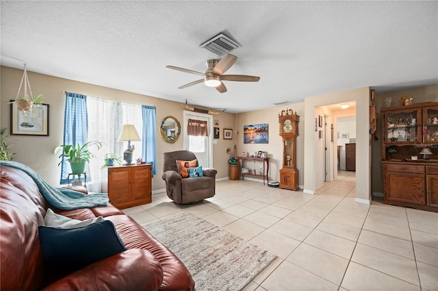 living room with ceiling fan, a textured ceiling, and light tile patterned floors