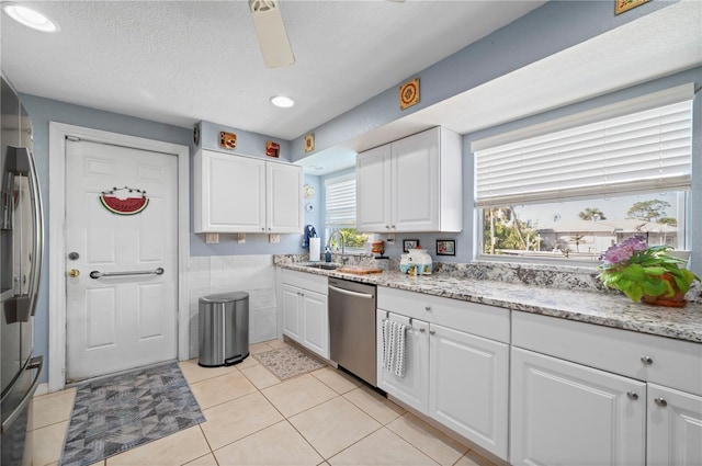 kitchen featuring light tile patterned floors, appliances with stainless steel finishes, a textured ceiling, white cabinetry, and sink