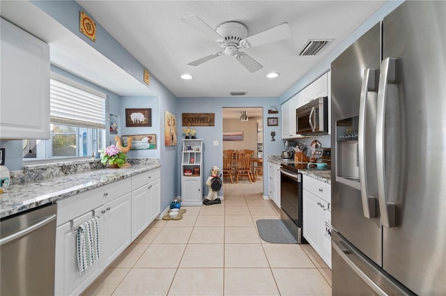 kitchen featuring stainless steel appliances, light stone countertops, light tile patterned floors, white cabinetry, and ceiling fan