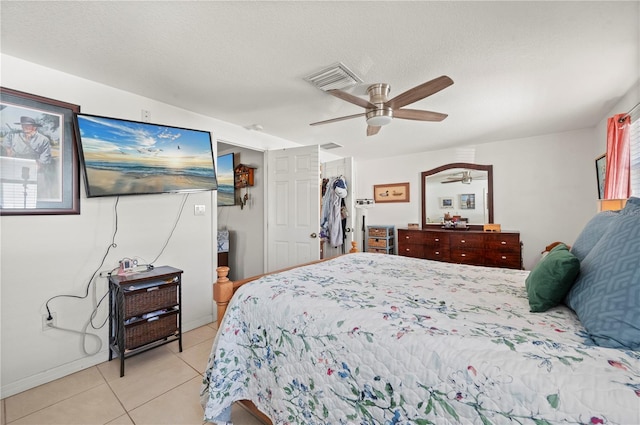 tiled bedroom with a spacious closet, ceiling fan, a closet, and a textured ceiling