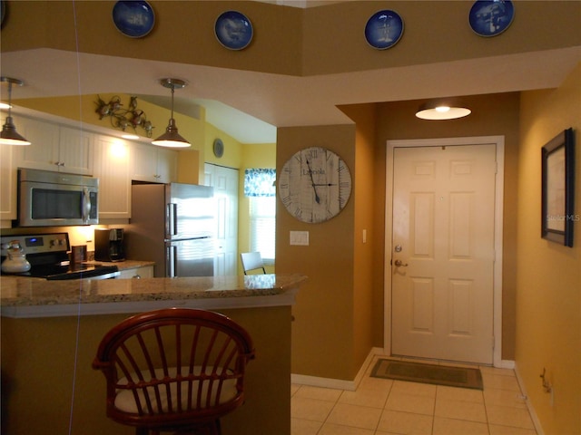 kitchen featuring light stone countertops, kitchen peninsula, hanging light fixtures, white cabinetry, and stainless steel appliances