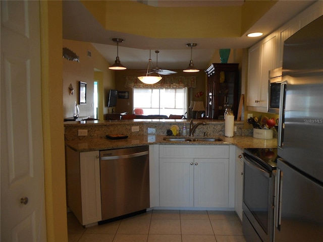 kitchen with kitchen peninsula, sink, white cabinets, decorative light fixtures, and appliances with stainless steel finishes