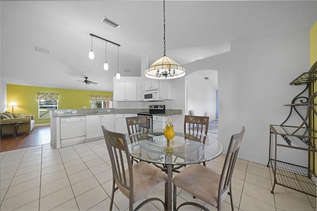 tiled dining area with ceiling fan with notable chandelier