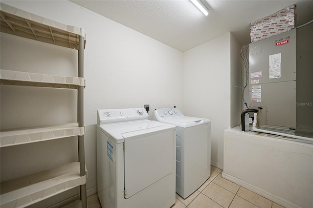 clothes washing area with a textured ceiling, heating unit, separate washer and dryer, and light tile patterned floors