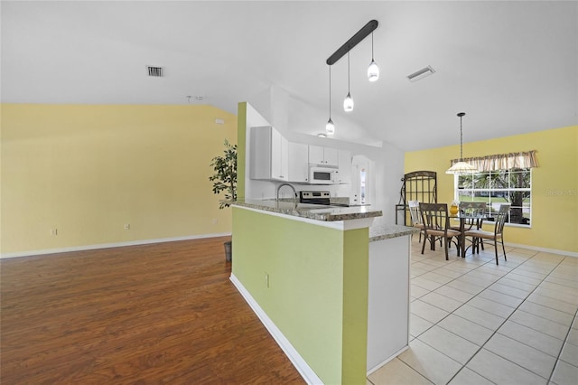 kitchen with lofted ceiling, kitchen peninsula, pendant lighting, white cabinets, and stainless steel electric range oven