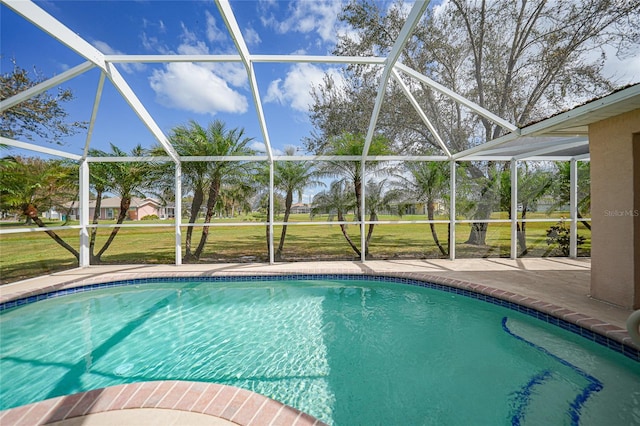 view of swimming pool featuring a yard, a patio, and a lanai