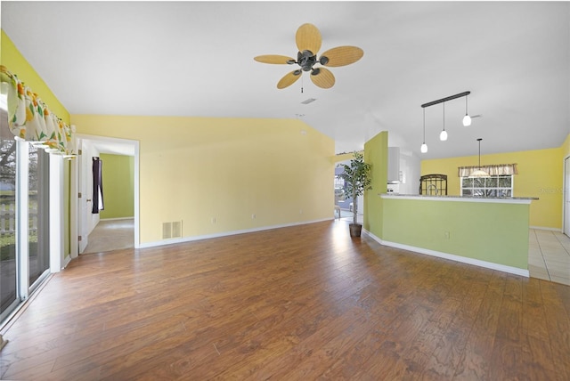 unfurnished living room with ceiling fan, lofted ceiling, a wealth of natural light, and hardwood / wood-style floors