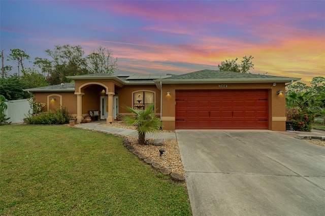 view of front of home featuring a garage, solar panels, and a yard