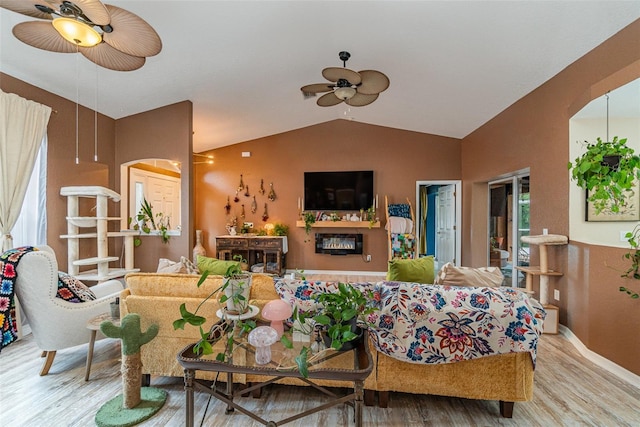 living room with light wood-type flooring, a wealth of natural light, vaulted ceiling, and ceiling fan