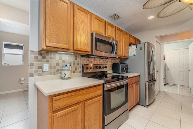 kitchen with stainless steel appliances, a textured ceiling, light tile patterned floors, and tasteful backsplash