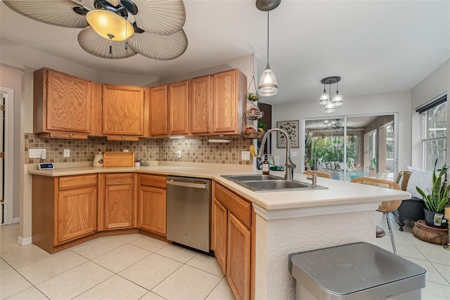 kitchen with backsplash, light tile patterned floors, hanging light fixtures, sink, and dishwasher