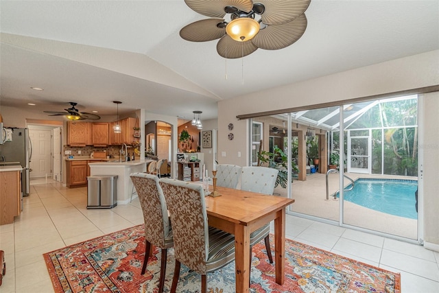 tiled dining space with lofted ceiling, ceiling fan, and sink