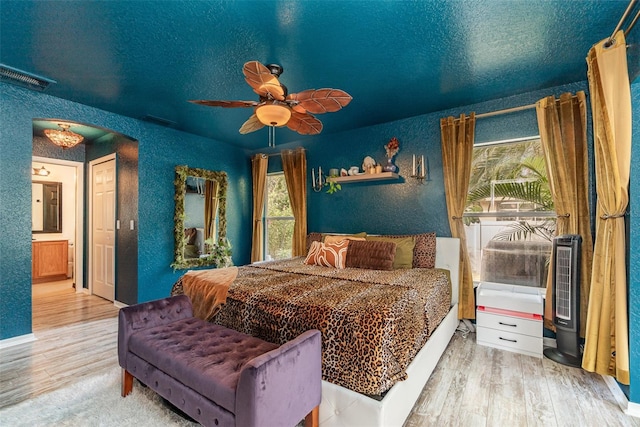 bedroom featuring connected bathroom, multiple windows, hardwood / wood-style floors, and ceiling fan