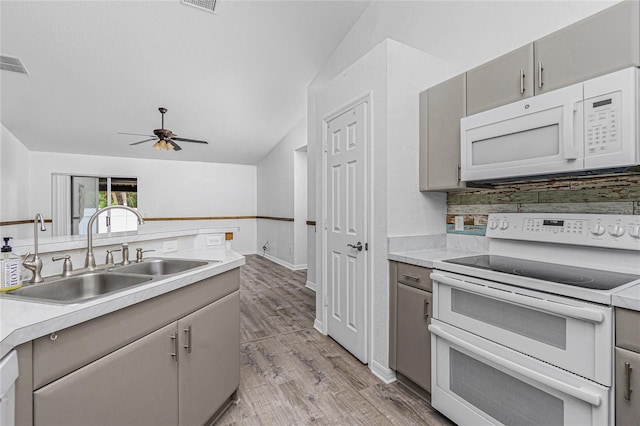 kitchen featuring light hardwood / wood-style flooring, gray cabinetry, sink, white appliances, and tasteful backsplash