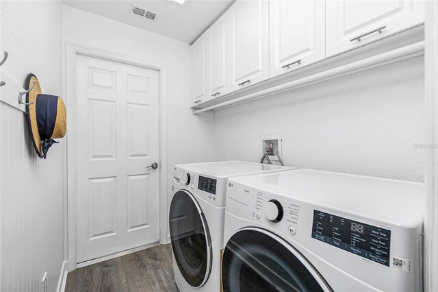 washroom with cabinets, washing machine and dryer, and dark hardwood / wood-style flooring