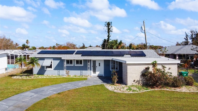 ranch-style home featuring solar panels and a front lawn