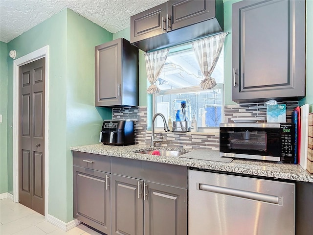 kitchen with tasteful backsplash, sink, stainless steel dishwasher, and gray cabinets