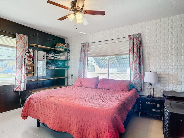 bedroom with brick wall, tile patterned floors, and ceiling fan