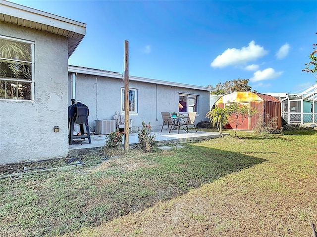 back of property with a patio, cooling unit, a yard, and glass enclosure