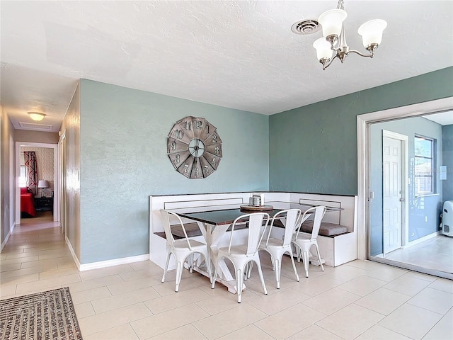 dining area with a chandelier, light tile patterned flooring, and a textured ceiling