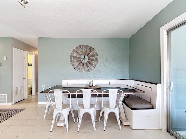 tiled dining space with a textured ceiling