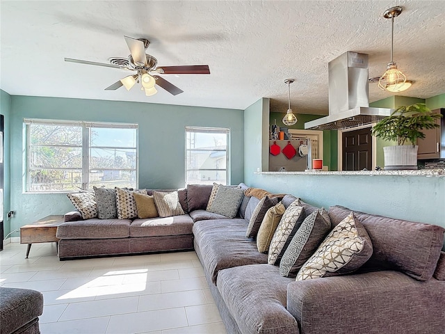 living room featuring ceiling fan, a textured ceiling, light tile patterned floors, and plenty of natural light