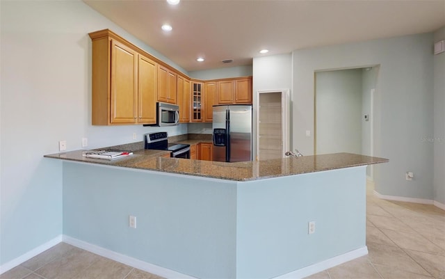 kitchen with kitchen peninsula, light tile patterned flooring, dark stone counters, and appliances with stainless steel finishes