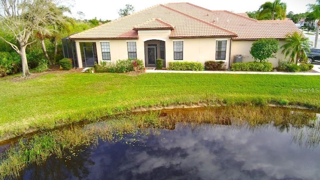 view of front facade featuring a front yard, a water view, stucco siding, and a tiled roof