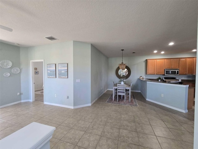 kitchen featuring stainless steel microwave, a notable chandelier, a textured ceiling, and visible vents