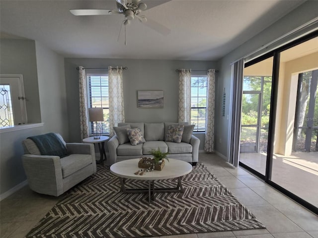 living room featuring light tile patterned floors, ceiling fan, baseboards, and plenty of natural light