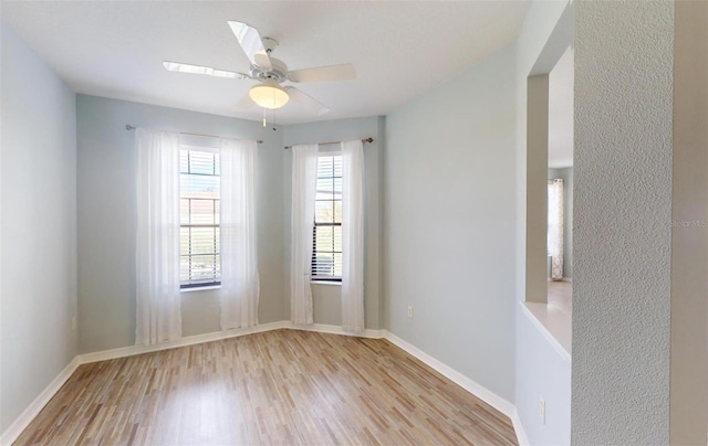 spare room with a ceiling fan, wood finished floors, and baseboards
