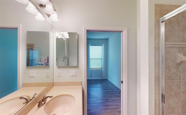 bathroom with vanity, a notable chandelier, a stall shower, baseboards, and wood finished floors