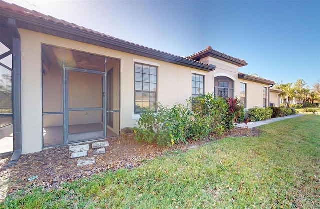 view of property exterior with a tile roof, a yard, and stucco siding